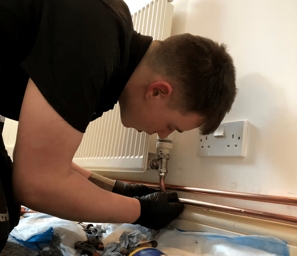 A plumber working on a radiator.